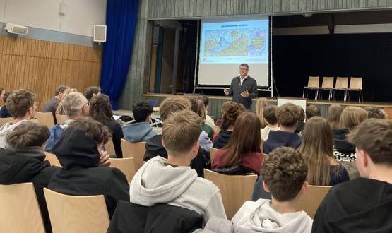 Ein Mann spricht vor vielen Schülerinnen und Schüler im Hörsaal