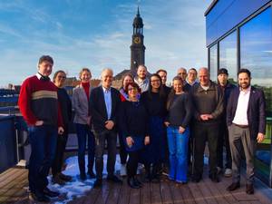Gruppenfoto auf der Dachterrasse der Katholischen Akademie Hamburg, im Hintergrund der Turm der Kirche St. Michaelis.